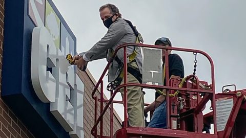 CEO putting up rebranded sign on building
