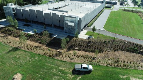 DCIM100MEDIADJI_0017.JPG A large parking garage with beautiful lawns and landscaping to the side of it.